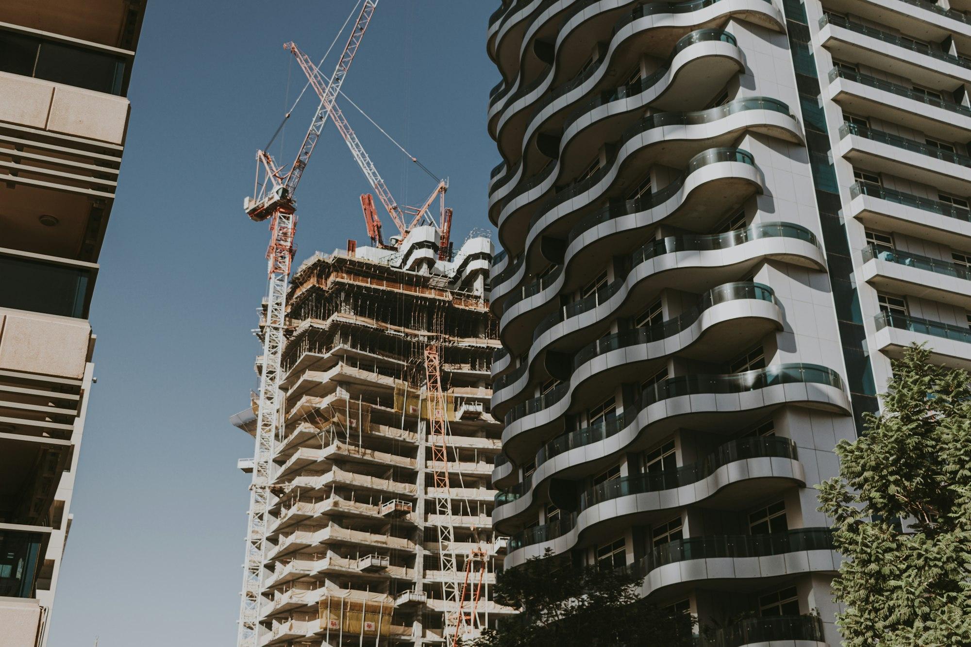 Two high-rise residential towers under construction against an overcast sky