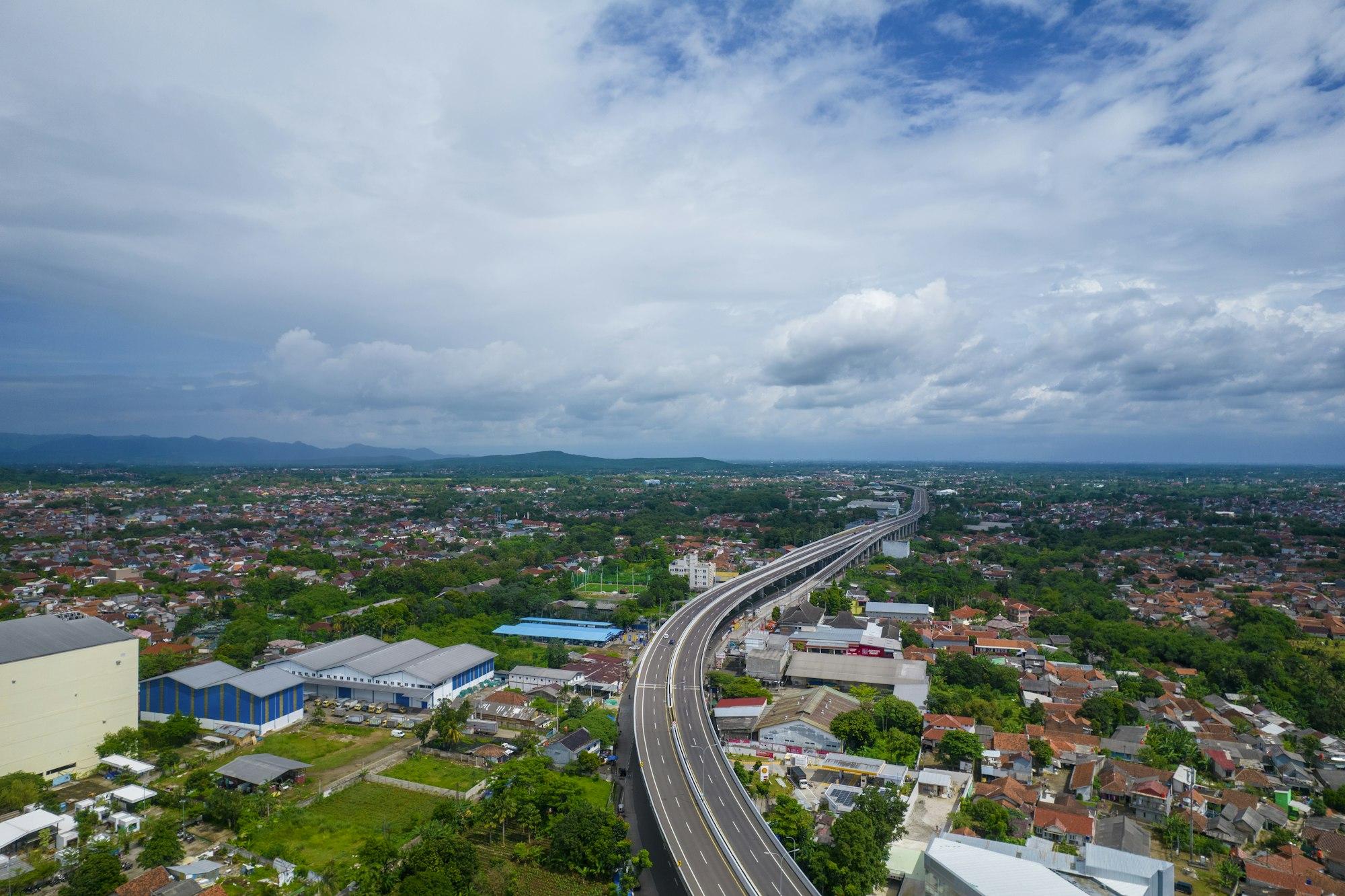 Aerial view of a multi-lane city highway junction running through a growing urban district